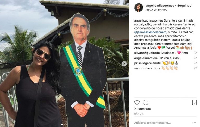 Fã tira foto com totem colocado na entrada do condomínio onde Bolsonaro mora
