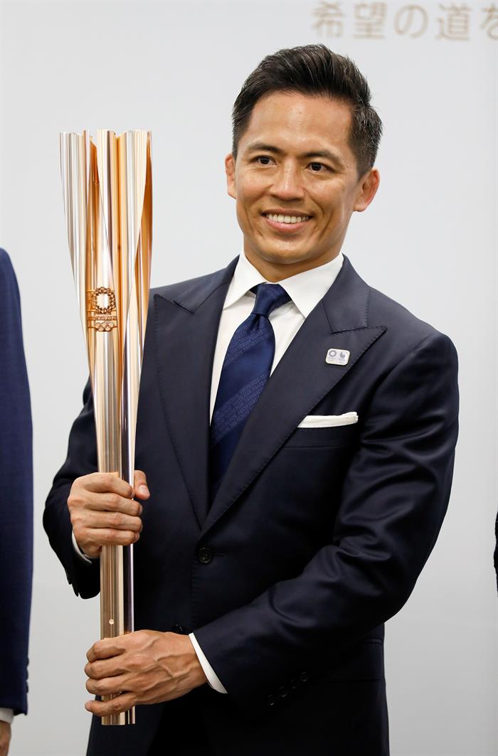  Tadahiro Nomura, tricampeão olímpico de judô, segura a tocha