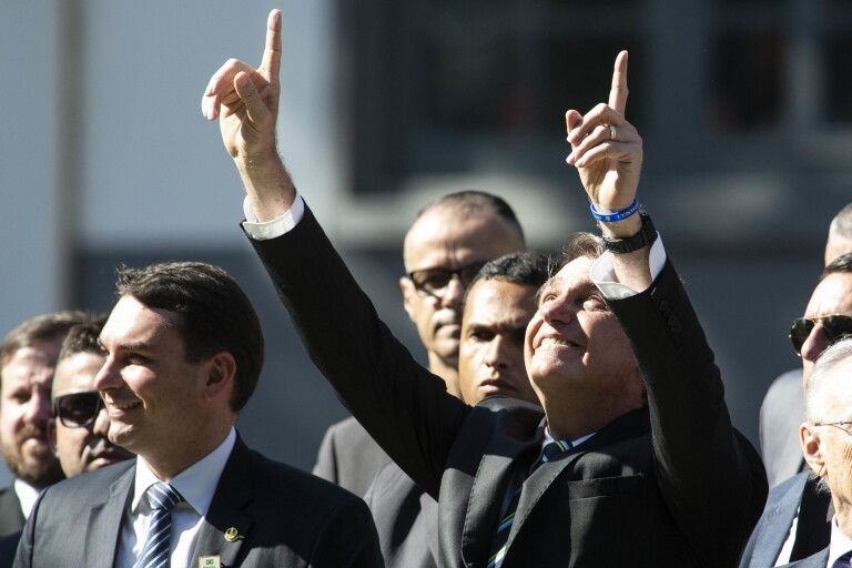 Presidente Jair Bolsonaro levanta as mãos para o céu durante evento em colégio militar
