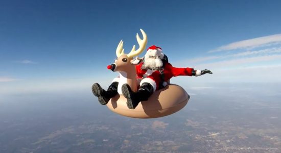 Papai Noel pulando de para-quedas com rena