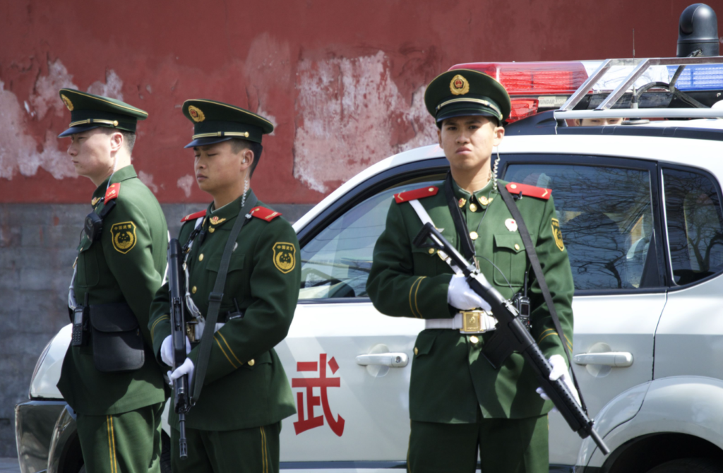 Policiais chineses armados em frente à viatura