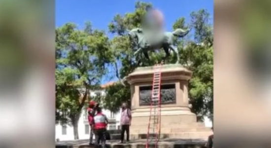 Homem sobe em estátua e tira a roupa para exigir vacina