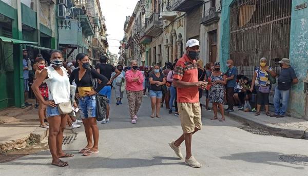 Várias pessoas com máscaras caminham por uma rua de Havana