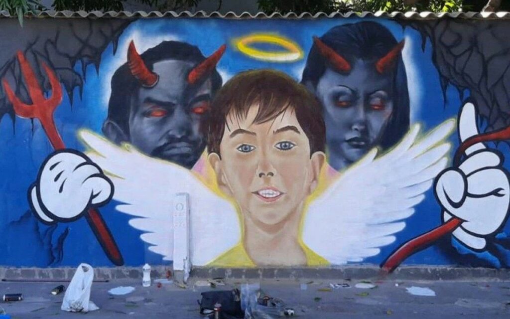 Artista de rua pinta Henry como anjo em frente a dois demônios