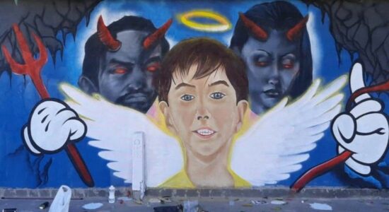 Artista de rua pinta Henry como anjo em frente a dois demônios