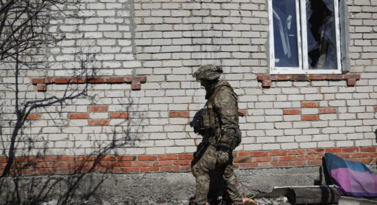Soldado das Forças de Defesa Territoriais inspeciona casas danificadas em uma área devastada pelo conflito no norte da região de Kharkiv, Ucrânia